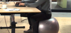 person sitting on stability ball at desk