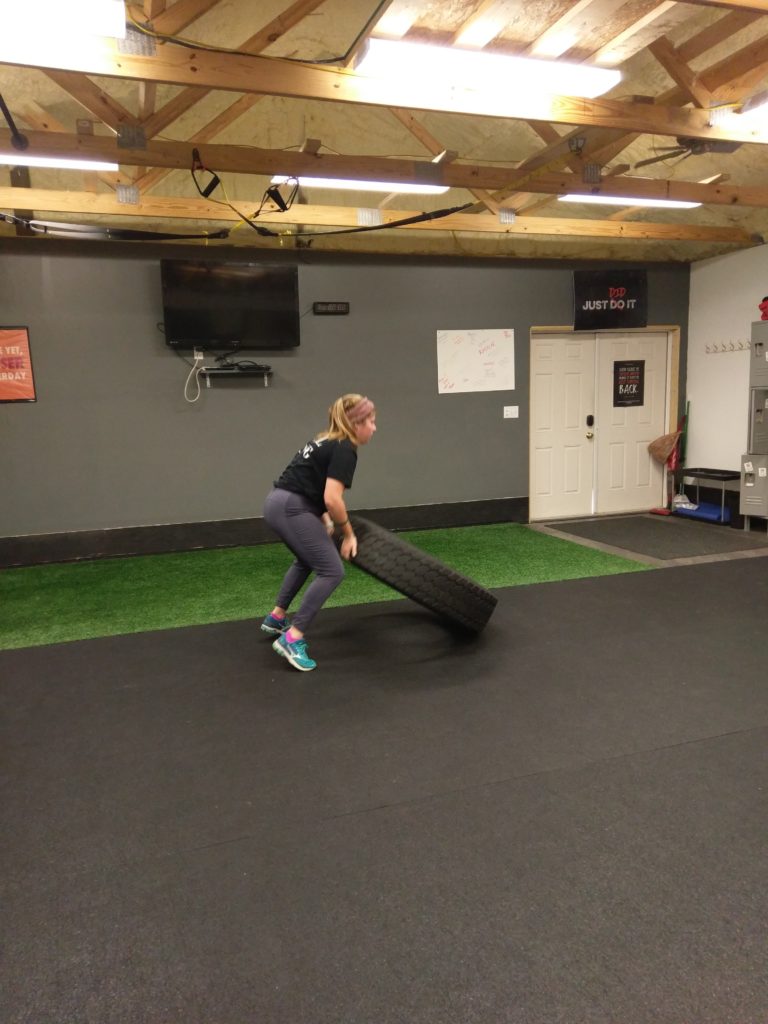 a woman flipping a tire in personal training session in catalyst 4 fitness studio