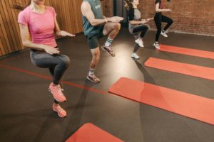 People performing high knees in an exercise class held in a gym