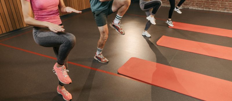 People performing high knees in an exercise class held in a gym