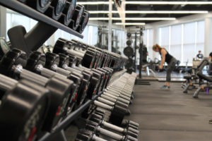 racks of dumbbells and a woman lifting weights