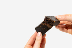 Hand holding unwrapped Peanut Butter Brownie Catalyst Bar