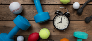 An alarm clock surrounded by sports balls and dumbbells