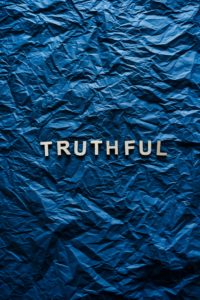 The word "TRUTHFUL" in silver capital letters on a blue background that looks like a piece of paper that has been flattened out after being crumpled