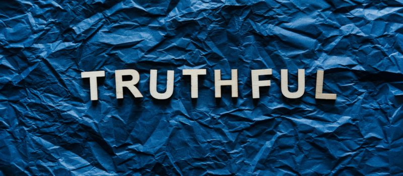 The word "TRUTHFUL" in silver capital letters on a blue background that looks like a piece of paper that has been flattened out after being crumpled